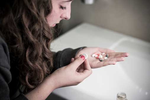 young woman looking at pill